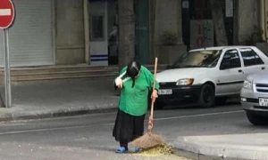 Bakıda qolu sarğılı qadın küçə süpürür -